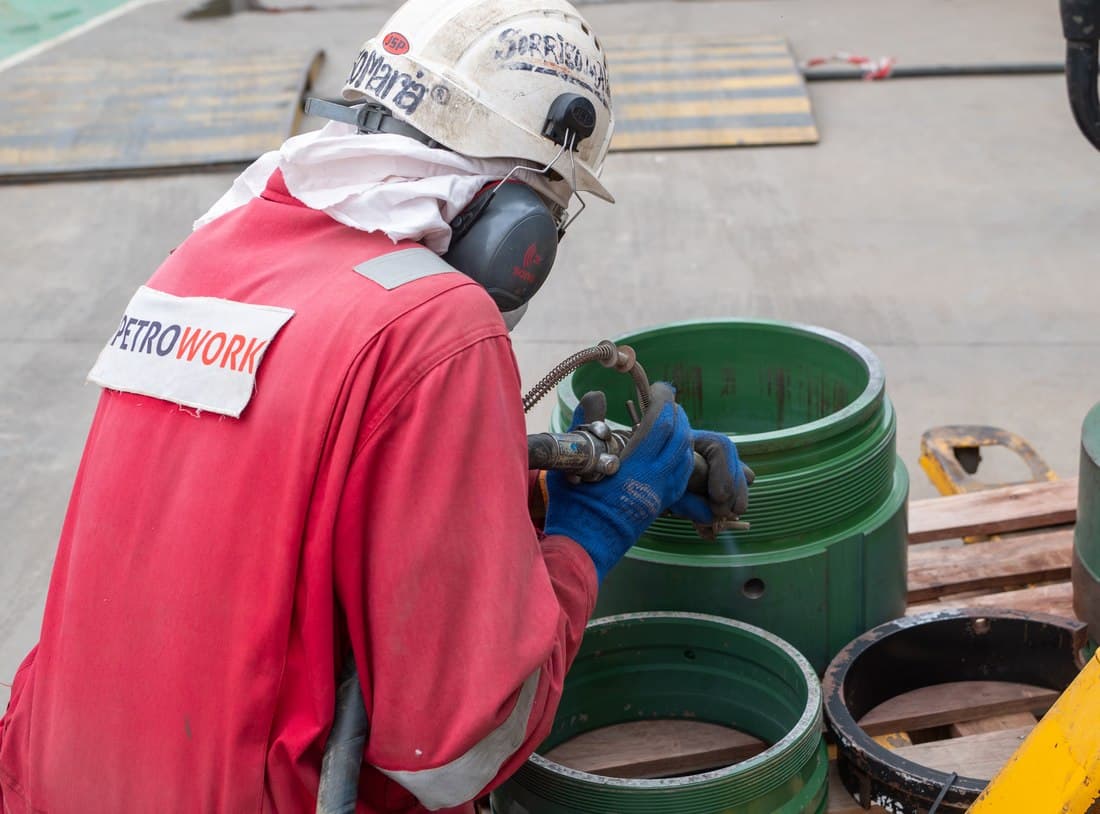 Technician in PPE working on a wellhead fitting