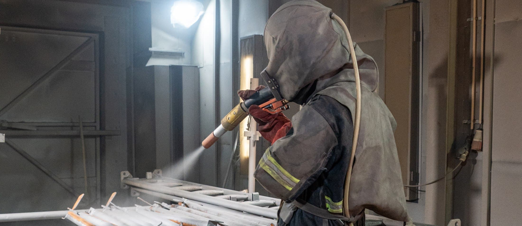 Technician abrasive blasting steelwork in the coatings booth