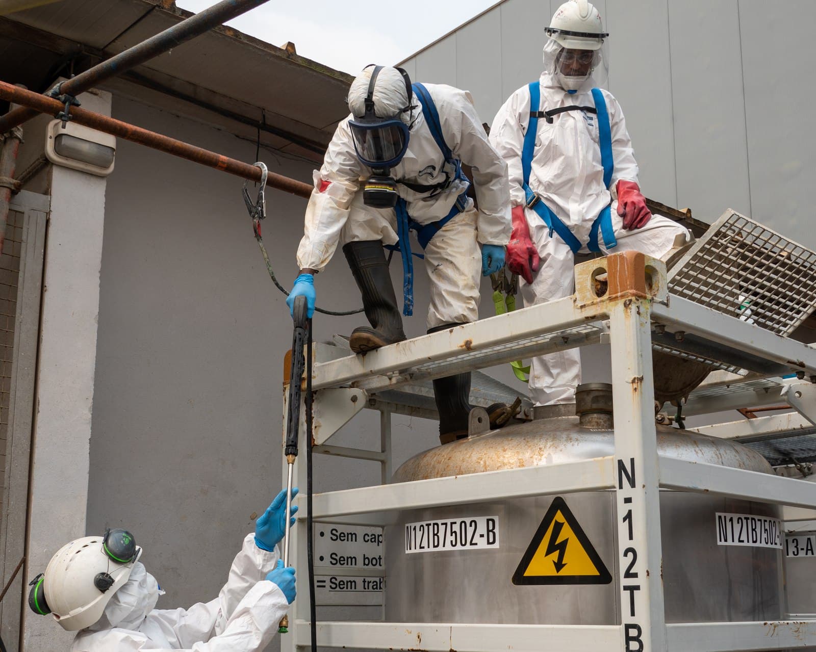 Technicians in full PPE cleaning a process tank